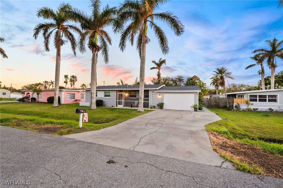 a view of a white house with a big yard and palm trees