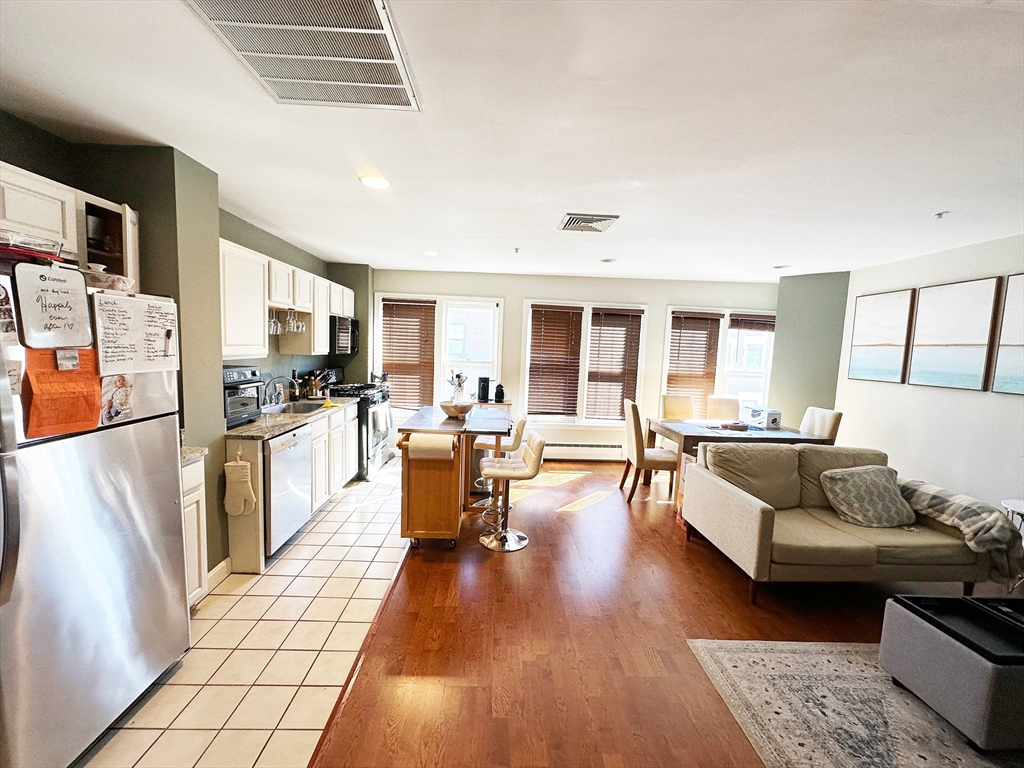 a living room with stainless steel appliances furniture and a kitchen view