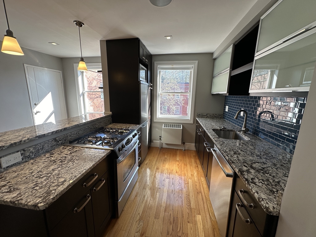 a kitchen with stainless steel appliances granite countertop a stove a sink dishwasher and a refrigerator