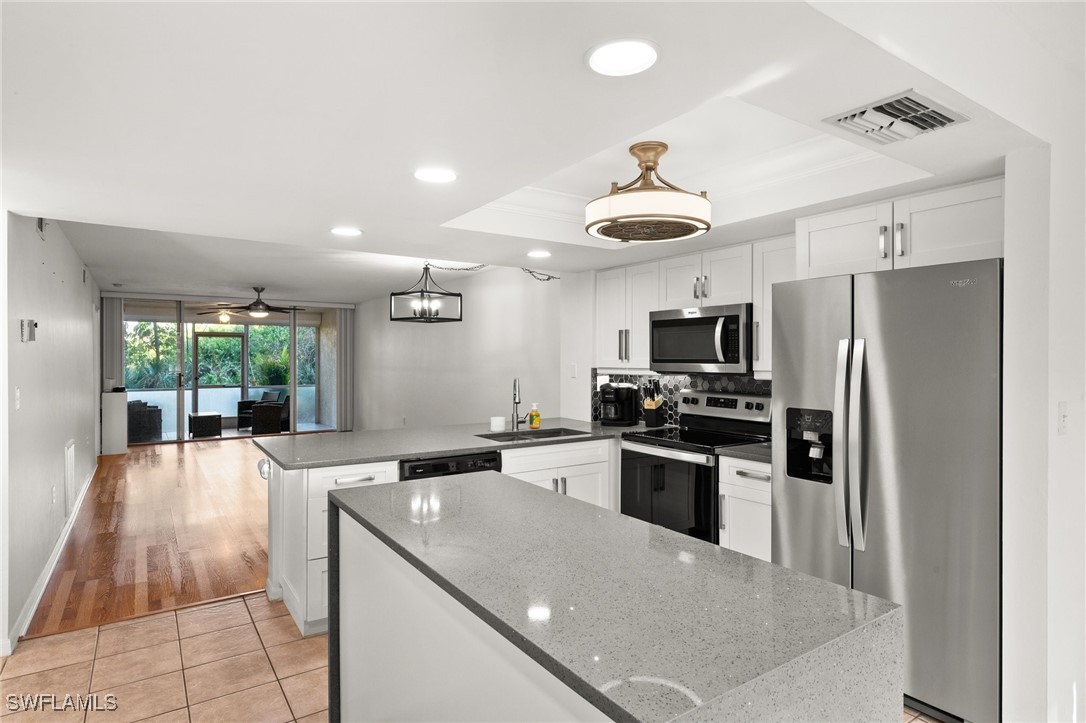 a kitchen with stainless steel appliances kitchen island granite countertop a refrigerator a sink dishwasher a stove and a dining table with wooden floor