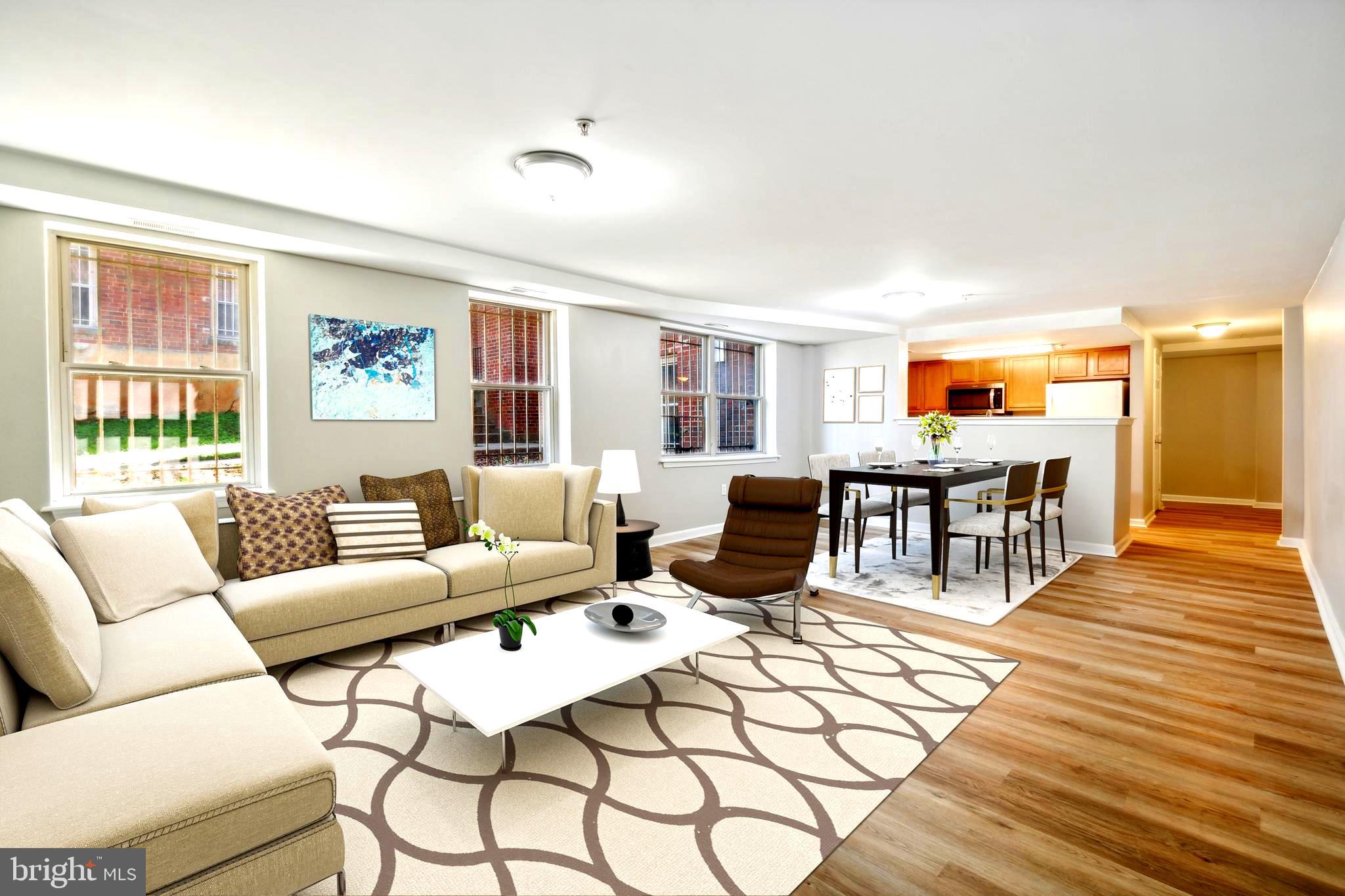 a living room with furniture two large window and a wooden floor