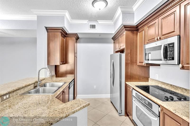 a kitchen with stainless steel appliances granite countertop a sink stove and refrigerator