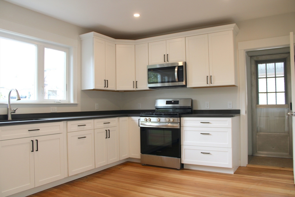 a kitchen with granite countertop white cabinets and appliances