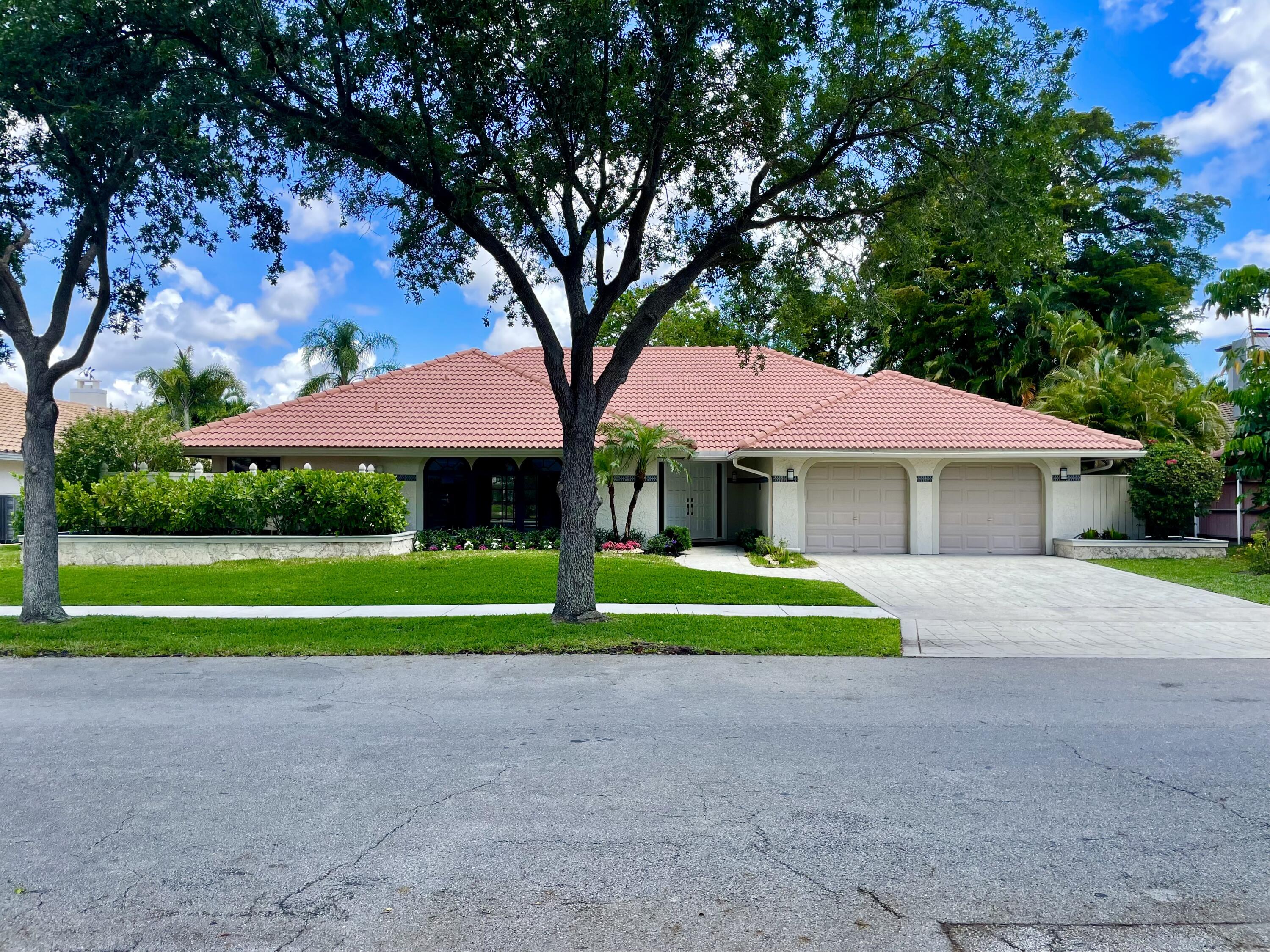 a front view of a house with garden and trees