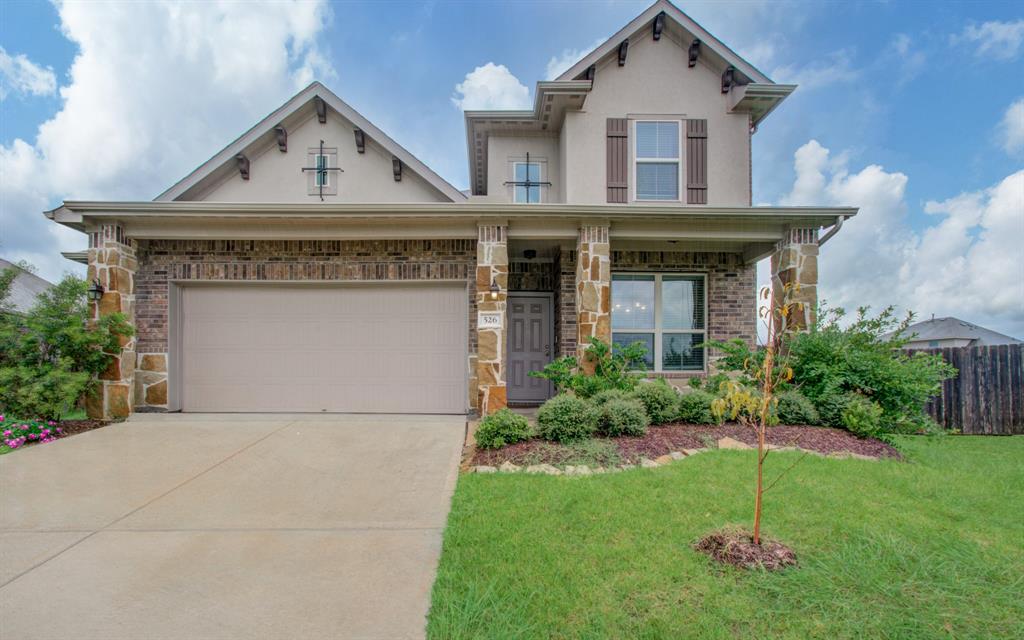 Charming two-story home featuring a stone and brick façade, with a two-car garage and well-maintained landscaping