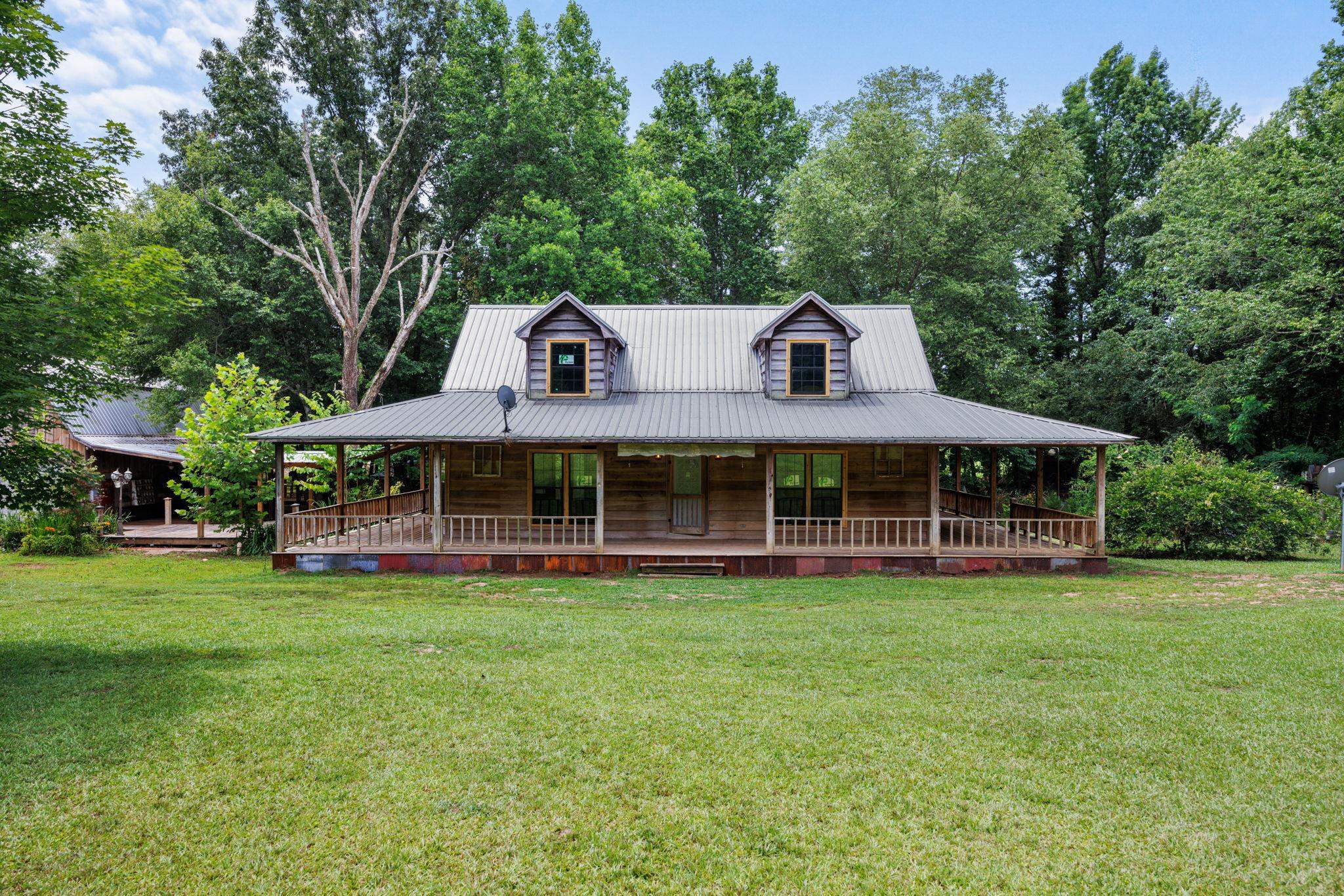 Farmhouse inspired home featuring covered porch and a front lawn