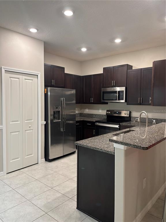 a kitchen with granite countertop a refrigerator and a stove top oven