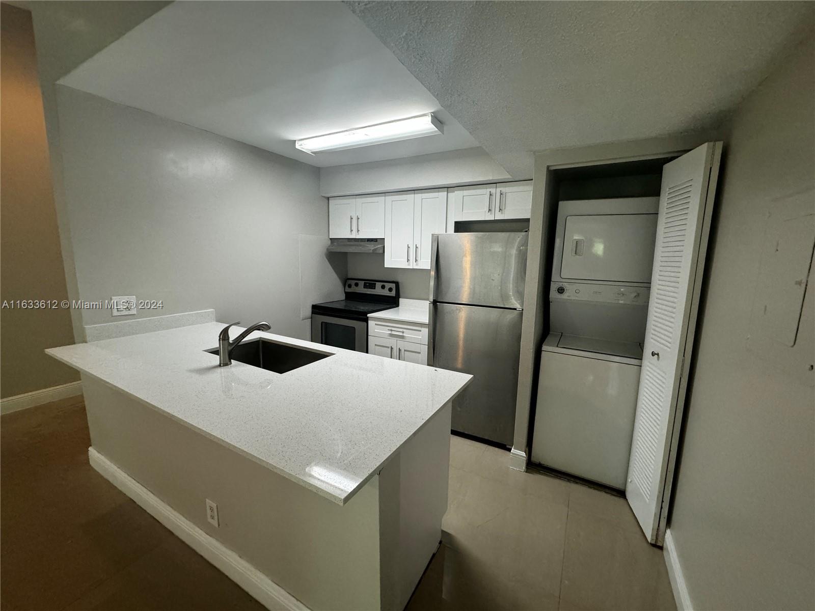 a kitchen that has a sink a refrigerator and a stove top oven