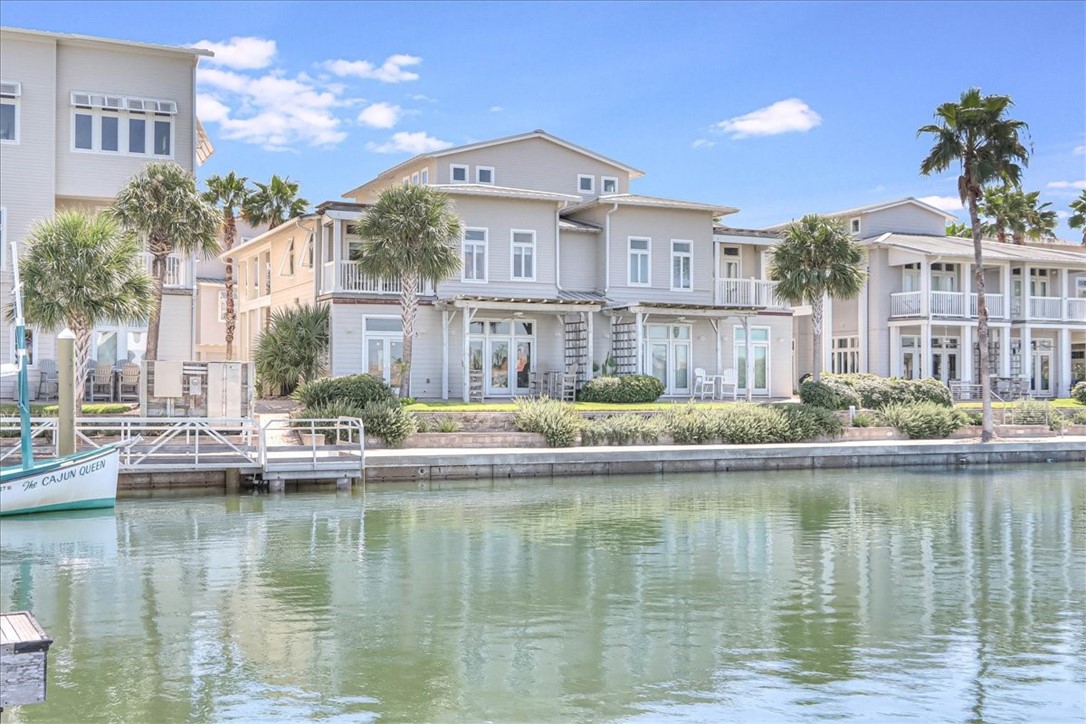 a front view of a building with river water fountain and a large tree