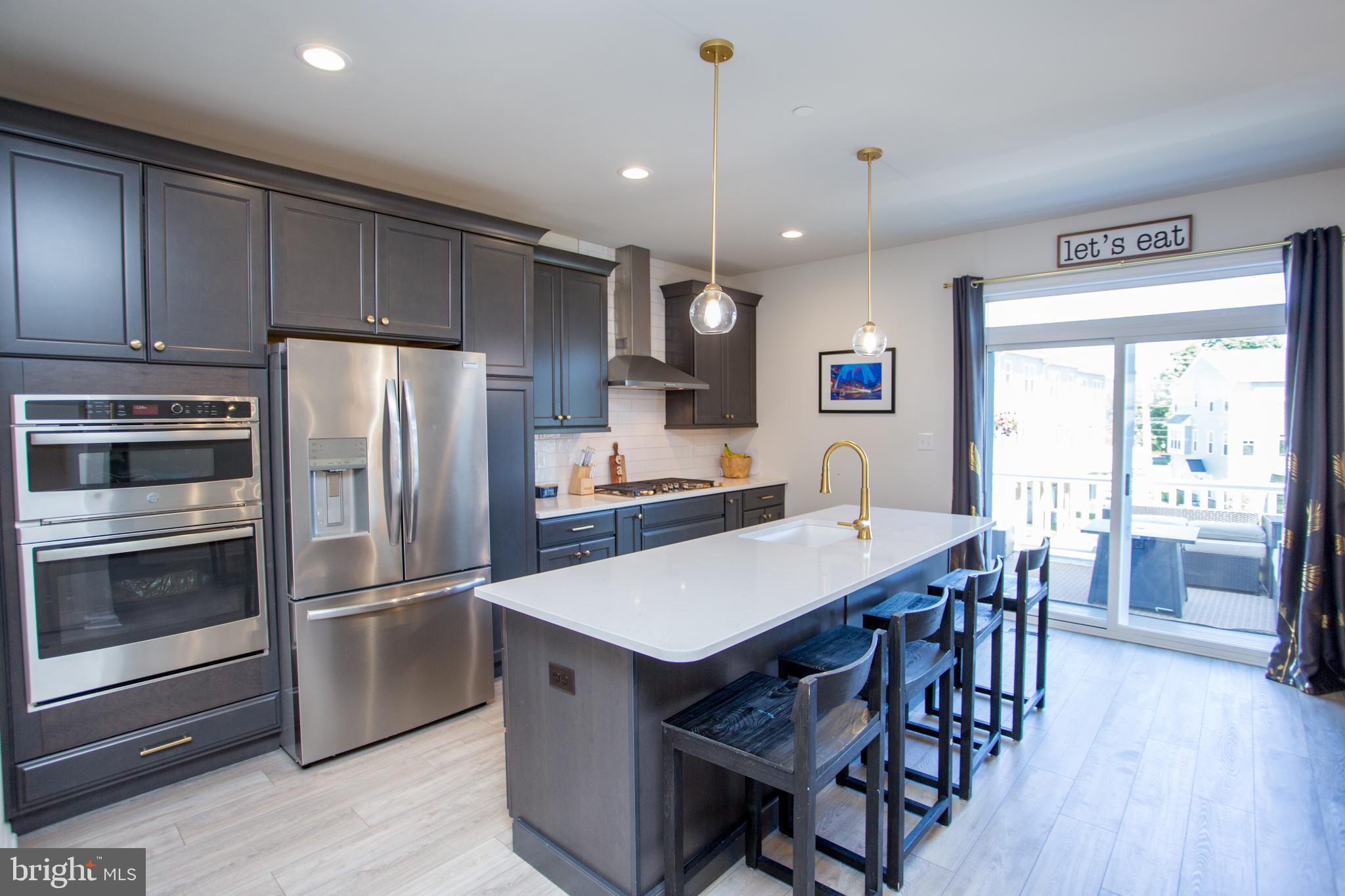 a kitchen with stainless steel appliances a dining table chairs refrigerator and cabinets