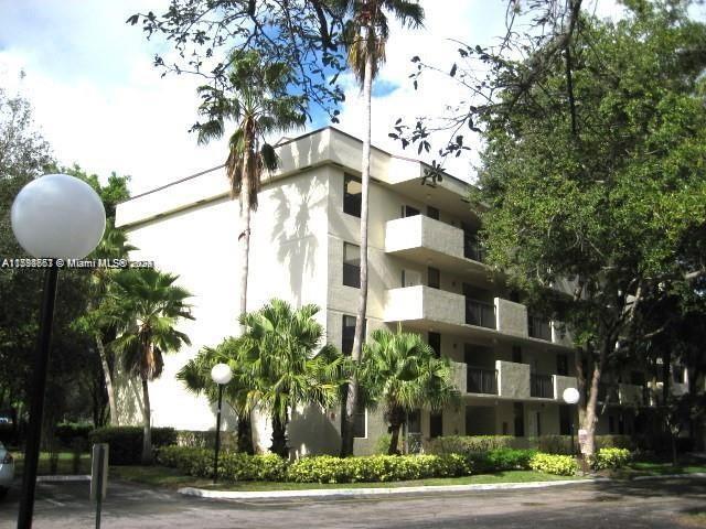 a front view of multi story residential apartment building with yard and sign board