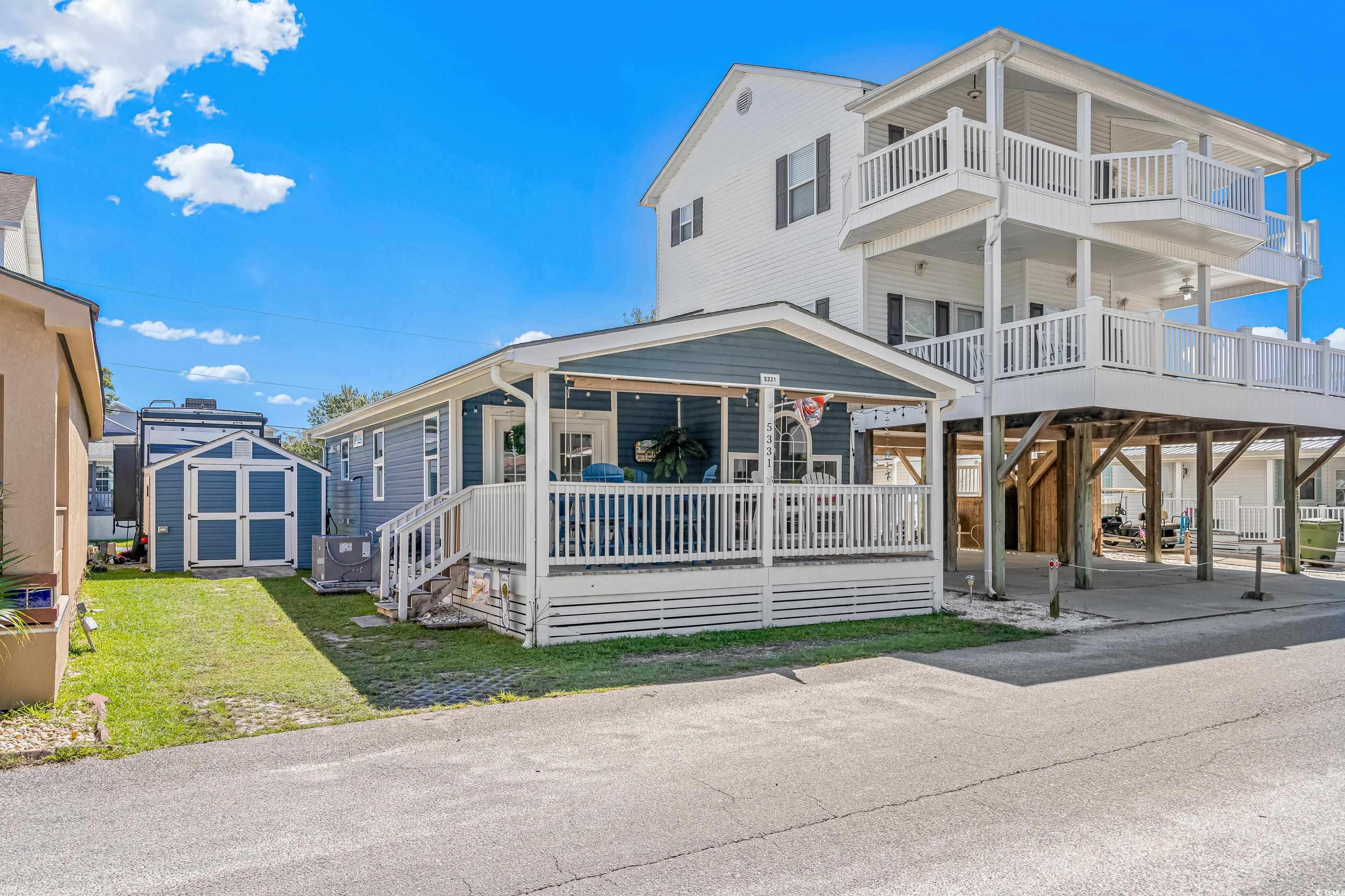 View of front of home with a porch, a shed, centra