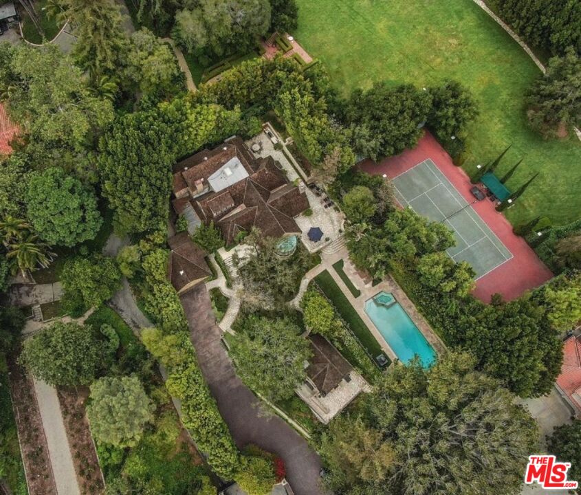 an aerial view of residential house with outdoor space and trees all around