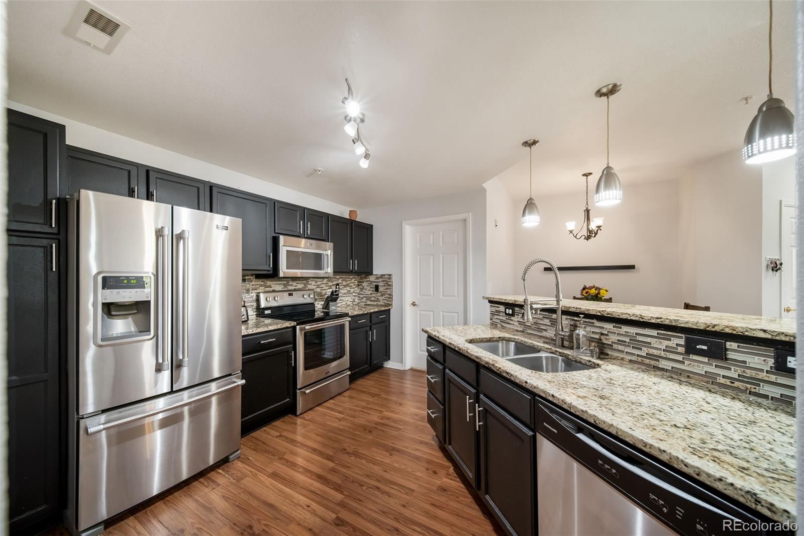 a kitchen with stainless steel appliances granite countertop a sink stove and refrigerator