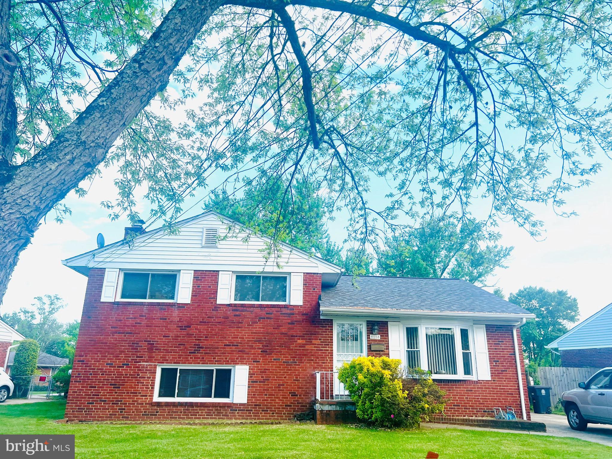 a front view of a house with garden and trees