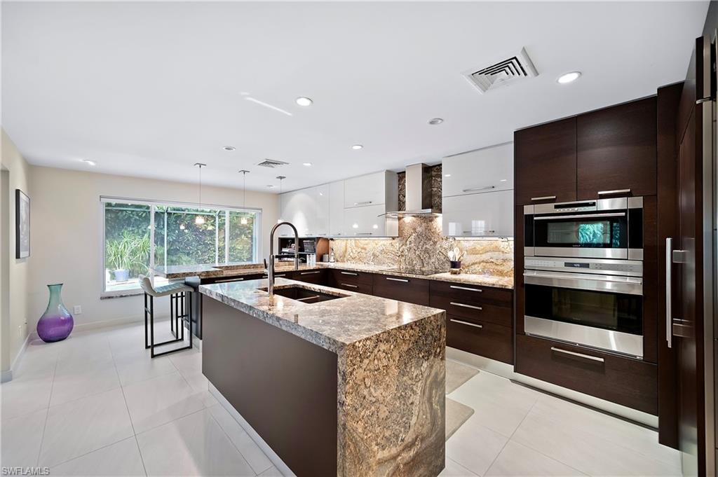 a kitchen with stainless steel appliances kitchen island granite countertop a stove and a sink