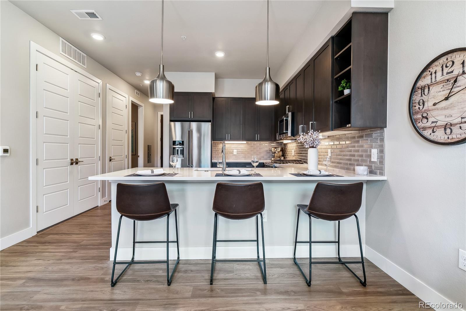 a kitchen with stainless steel appliances kitchen island granite countertop a table chairs and a wooden floor