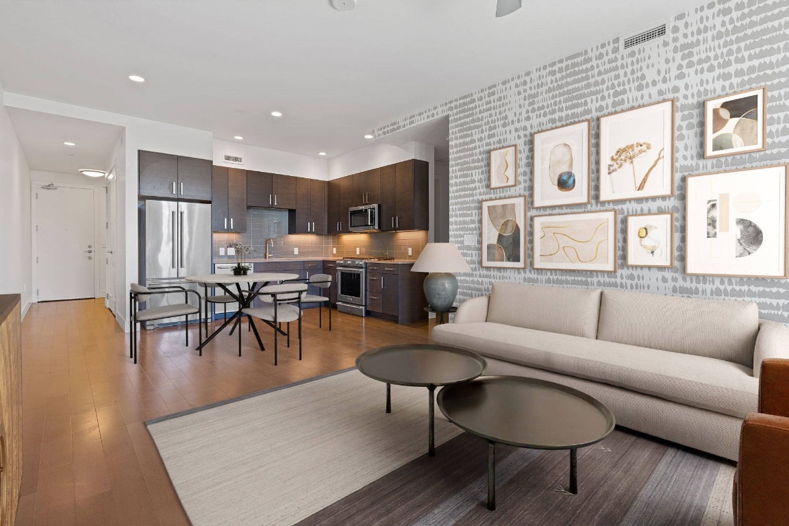 a living room with furniture kitchen view and a large window