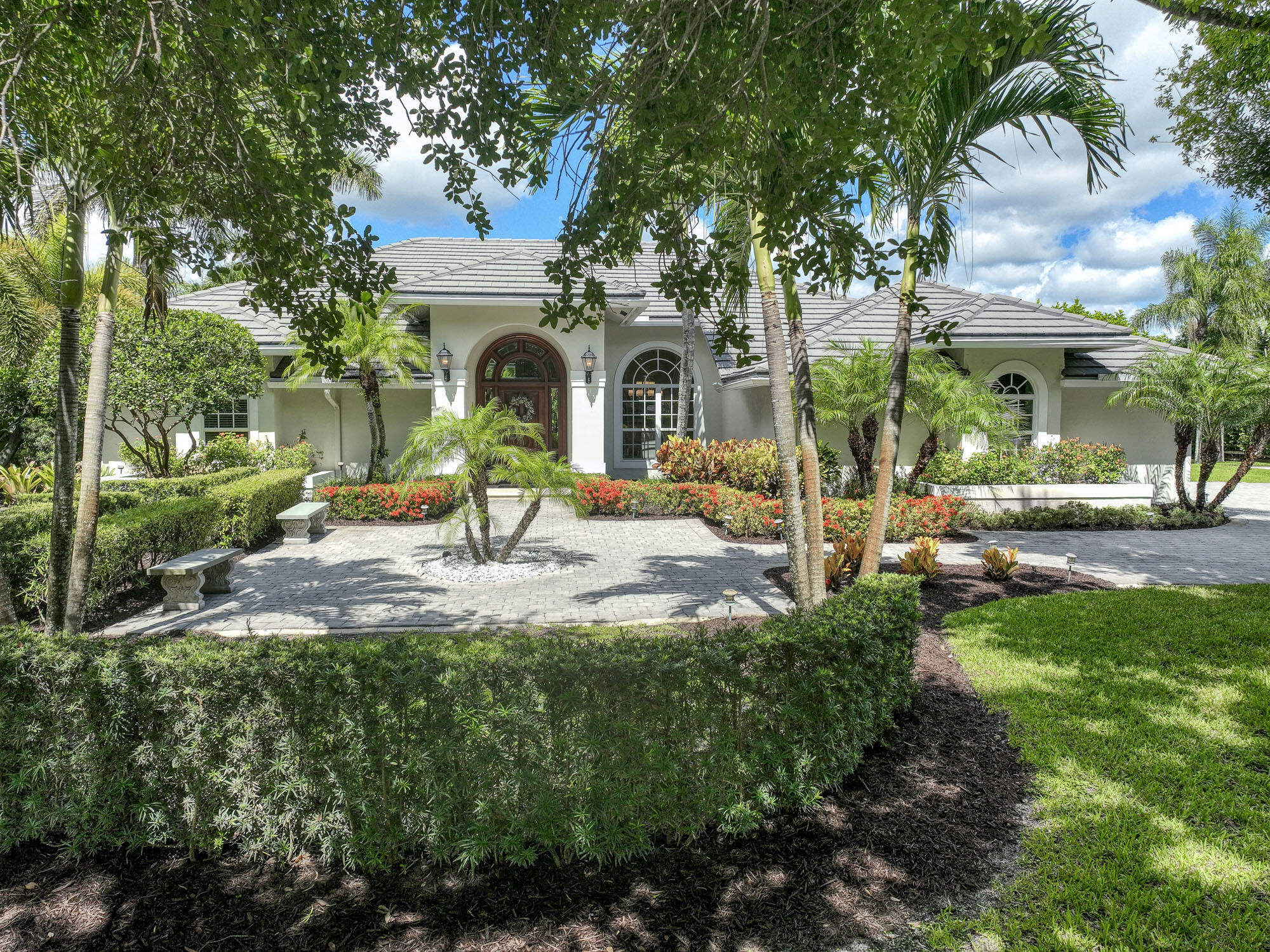 a front view of a house with garden and trees