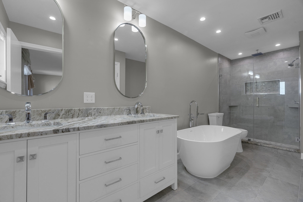 a bathroom with a double vanity sink mirror and bathtub