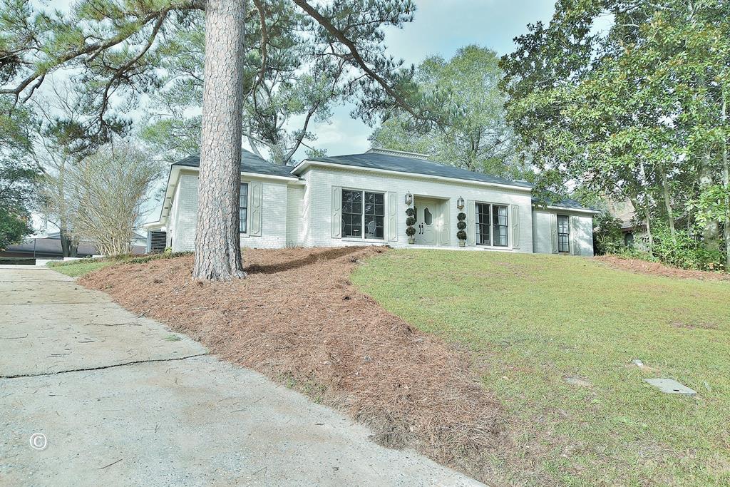 a front view of a house with a garden and trees