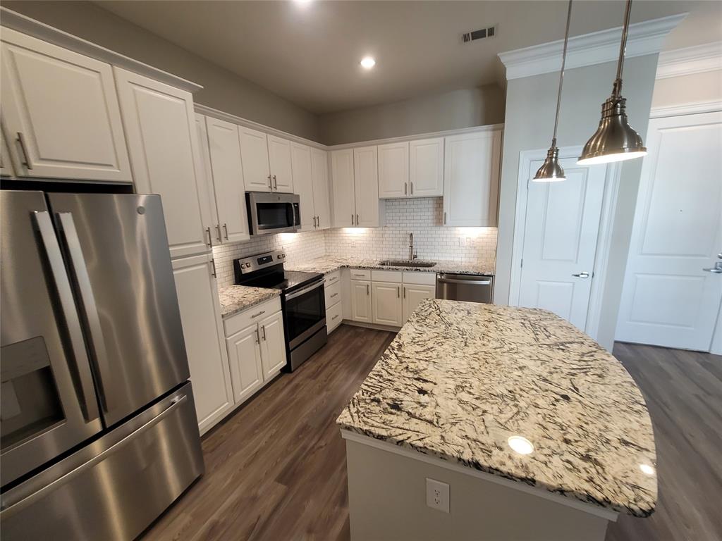 a kitchen with granite countertop a refrigerator stove and sink