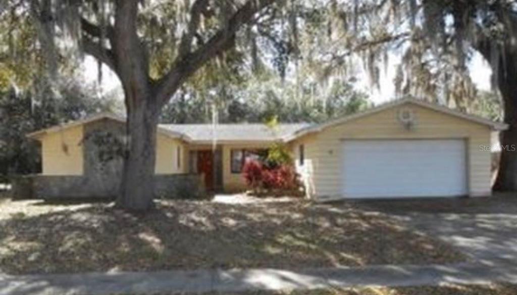 a view of a house with a yard and large tree