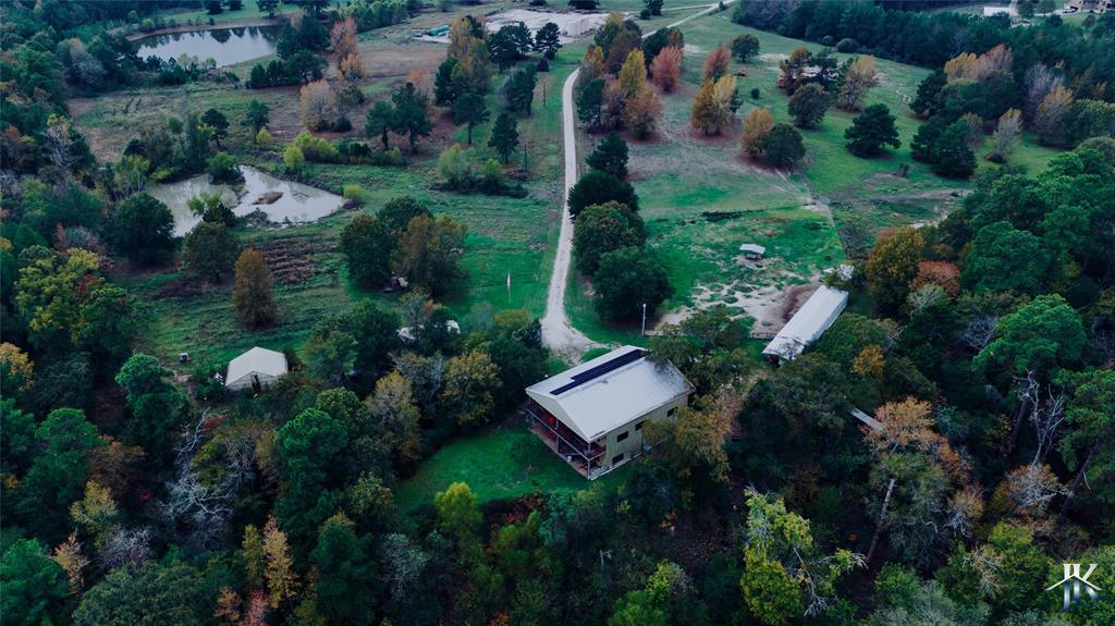 an aerial view of residential house with outdoor space and trees all around