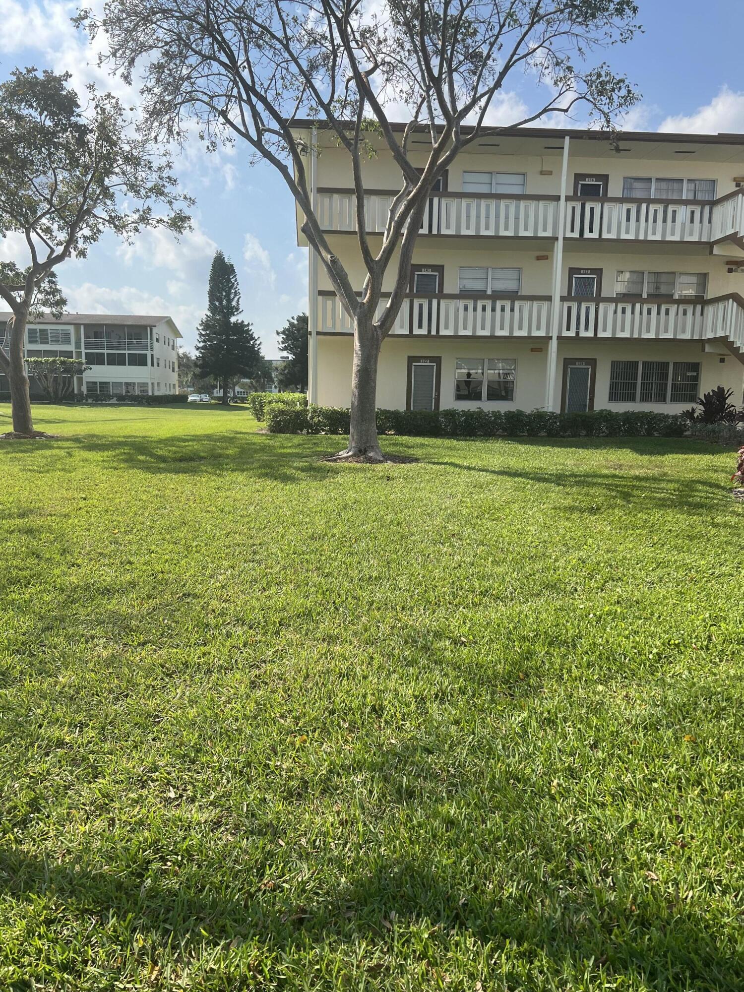 a view of a building with a big yard and large trees