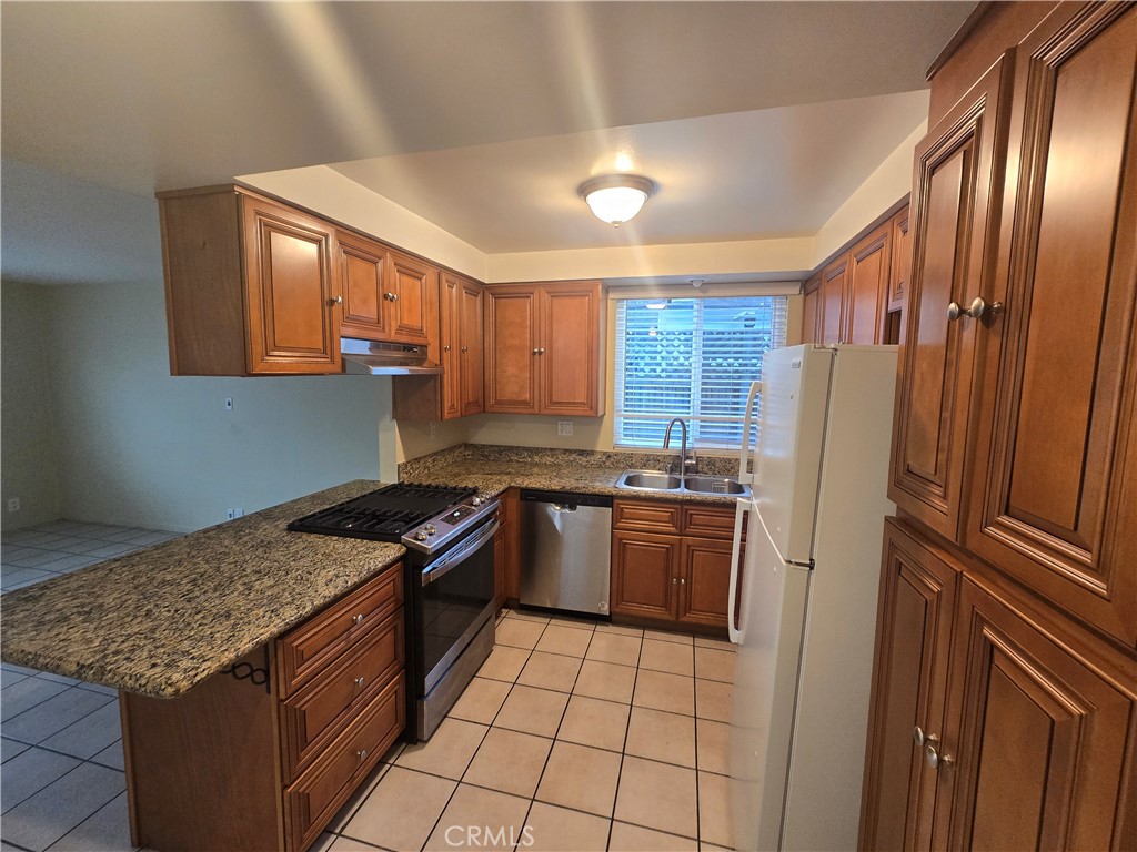 a kitchen with stainless steel appliances granite countertop a stove a refrigerator and a sink