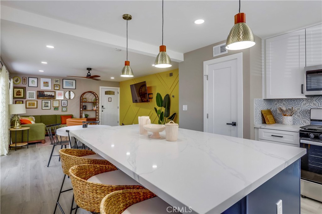 a kitchen with stainless steel appliances granite countertop a sink a stove top oven a chimney and a center island