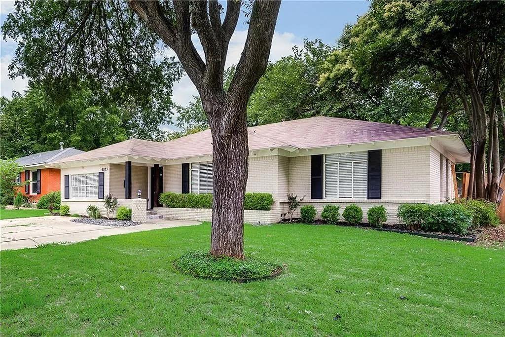 a front view of a house with a yard and trees