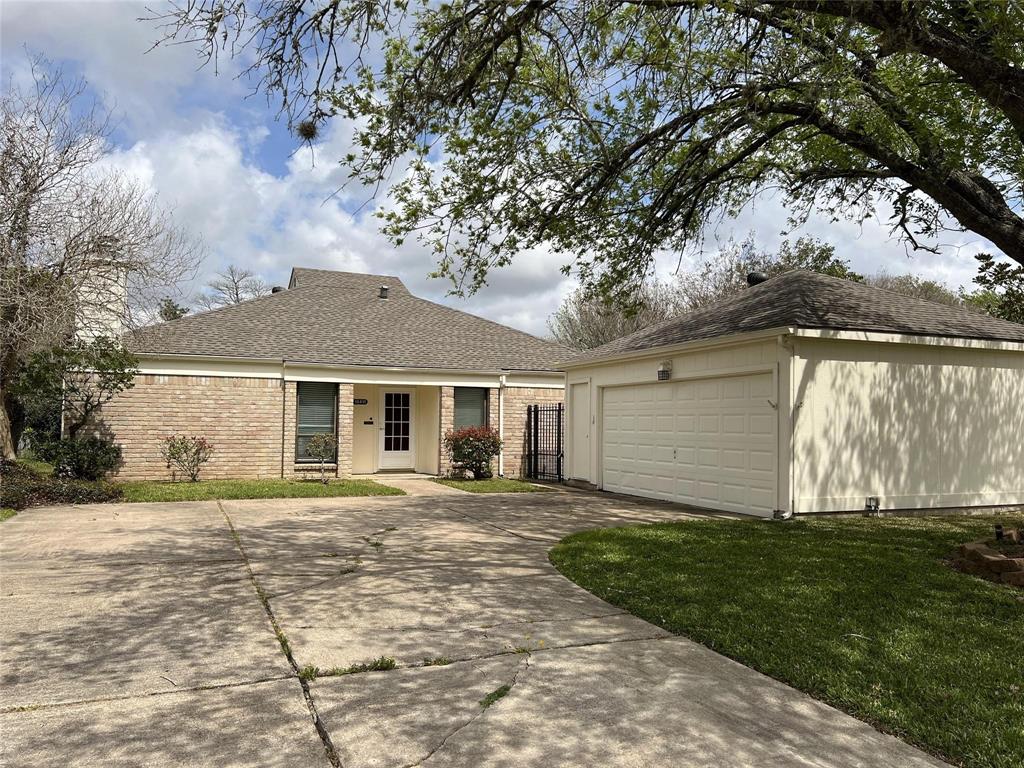 This is a single-story, brick-front home with a two-car garage, situated in a neighborhood with mature trees.