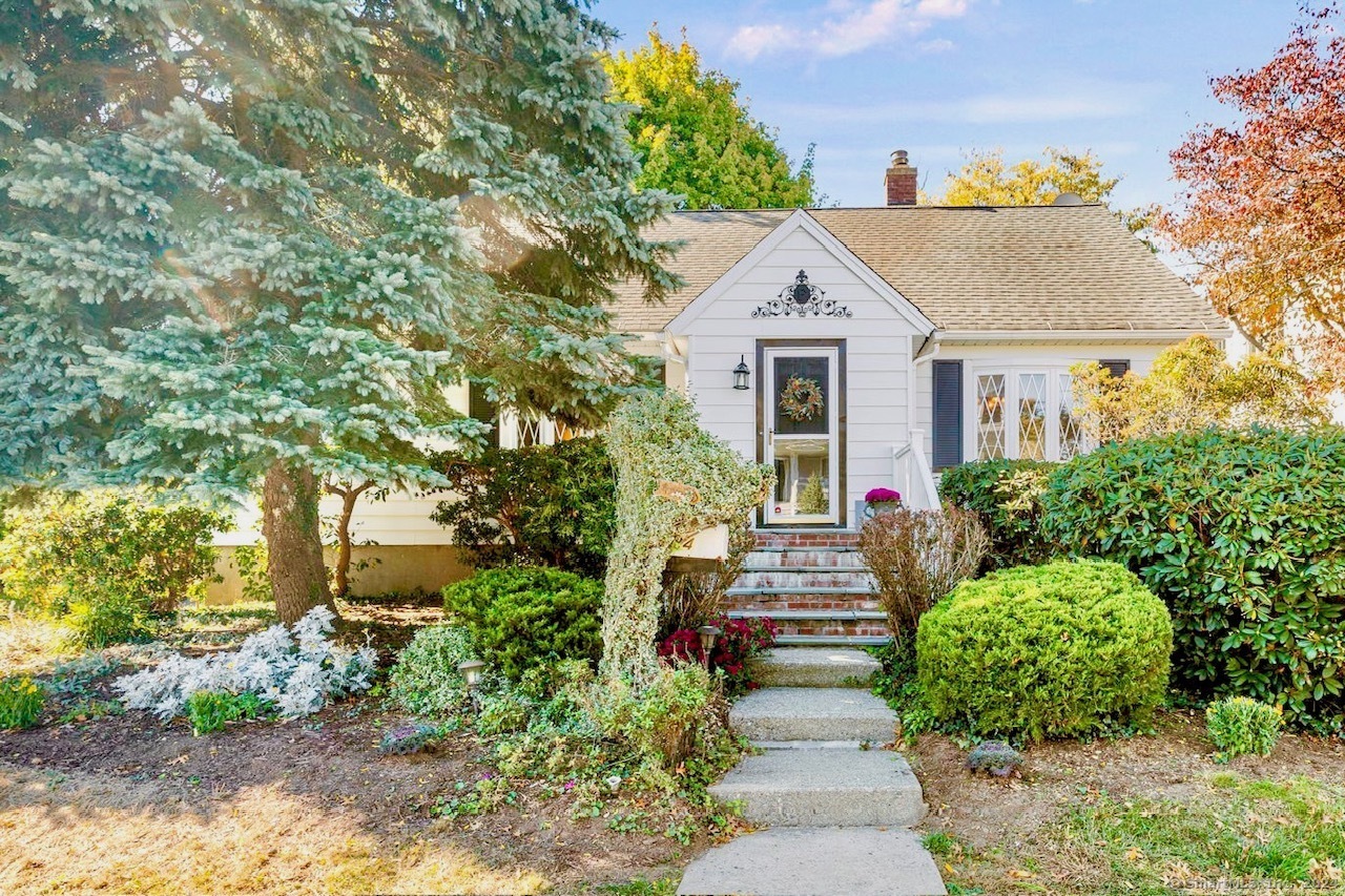 a view of a white house next to a yard with potted plants