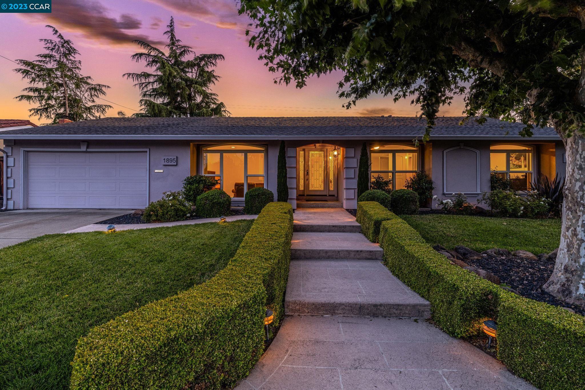 a front view of a house with a yard and potted plants