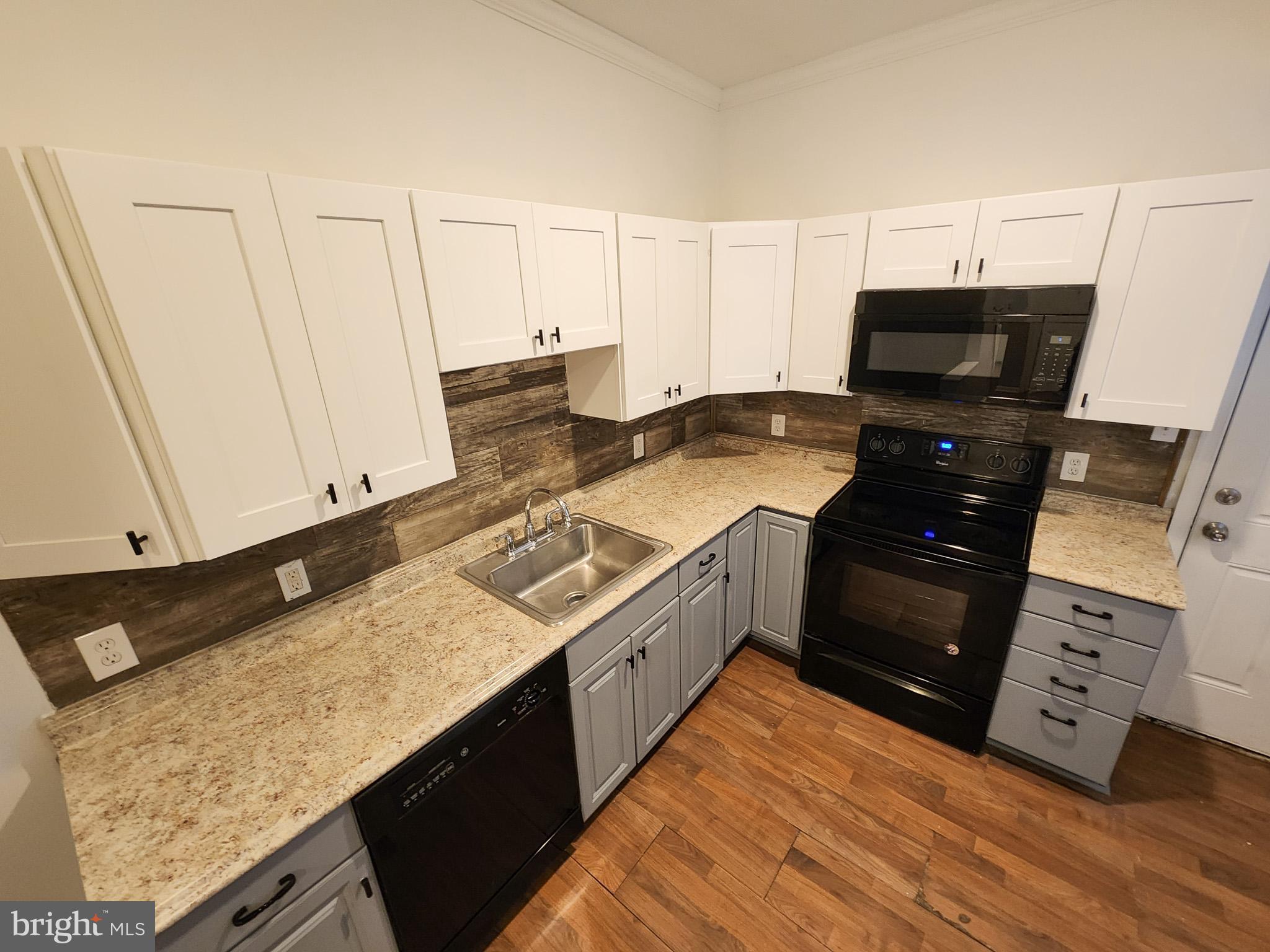 a kitchen with granite countertop a sink stove and cabinets