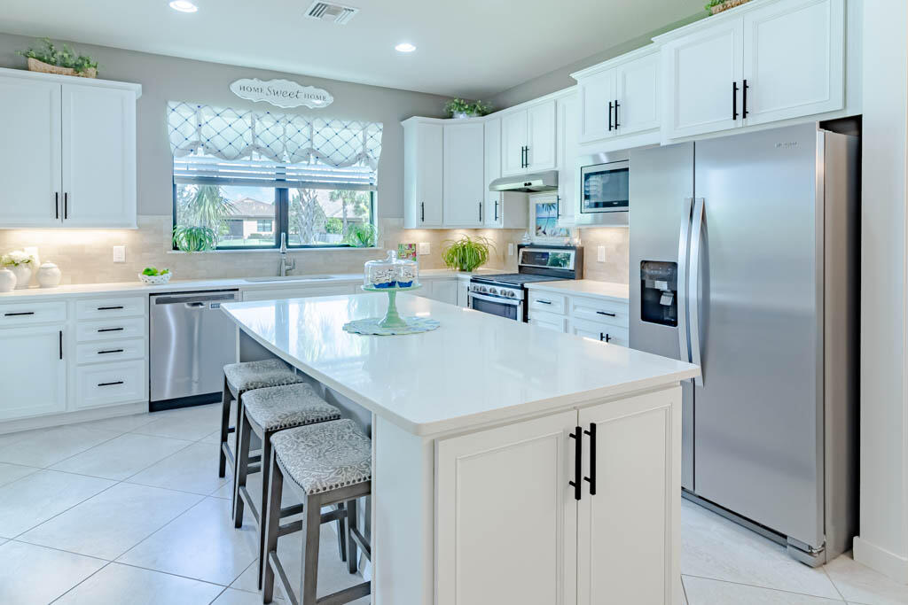 a kitchen with stainless steel appliances a refrigerator a sink a stove and white cabinets with wooden floor