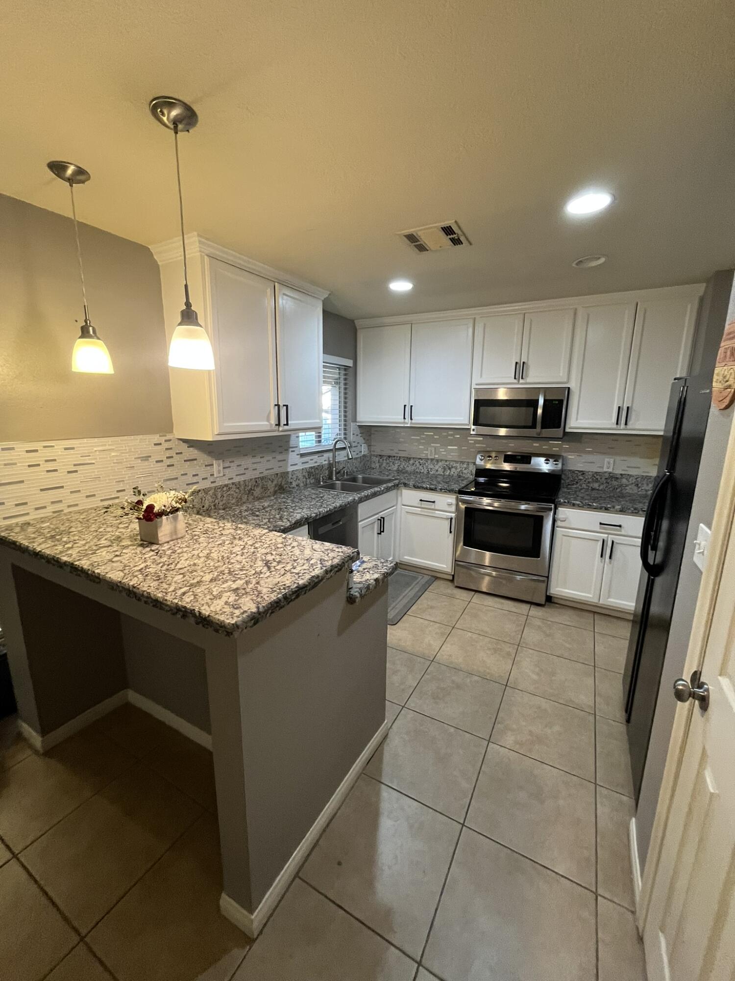 a kitchen with kitchen island granite countertop a sink counter top space appliances and cabinets