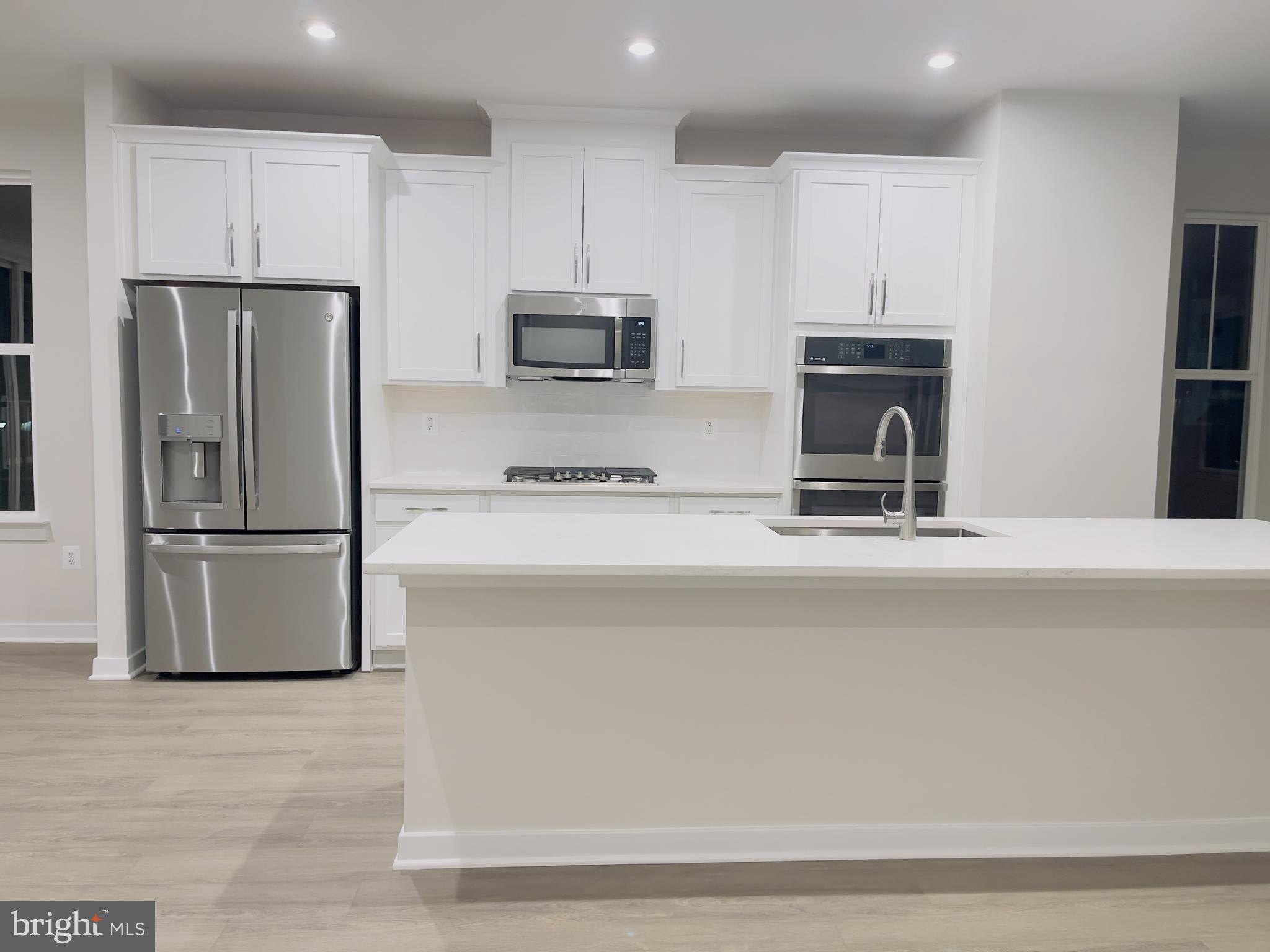 a kitchen with kitchen island a refrigerator and a sink