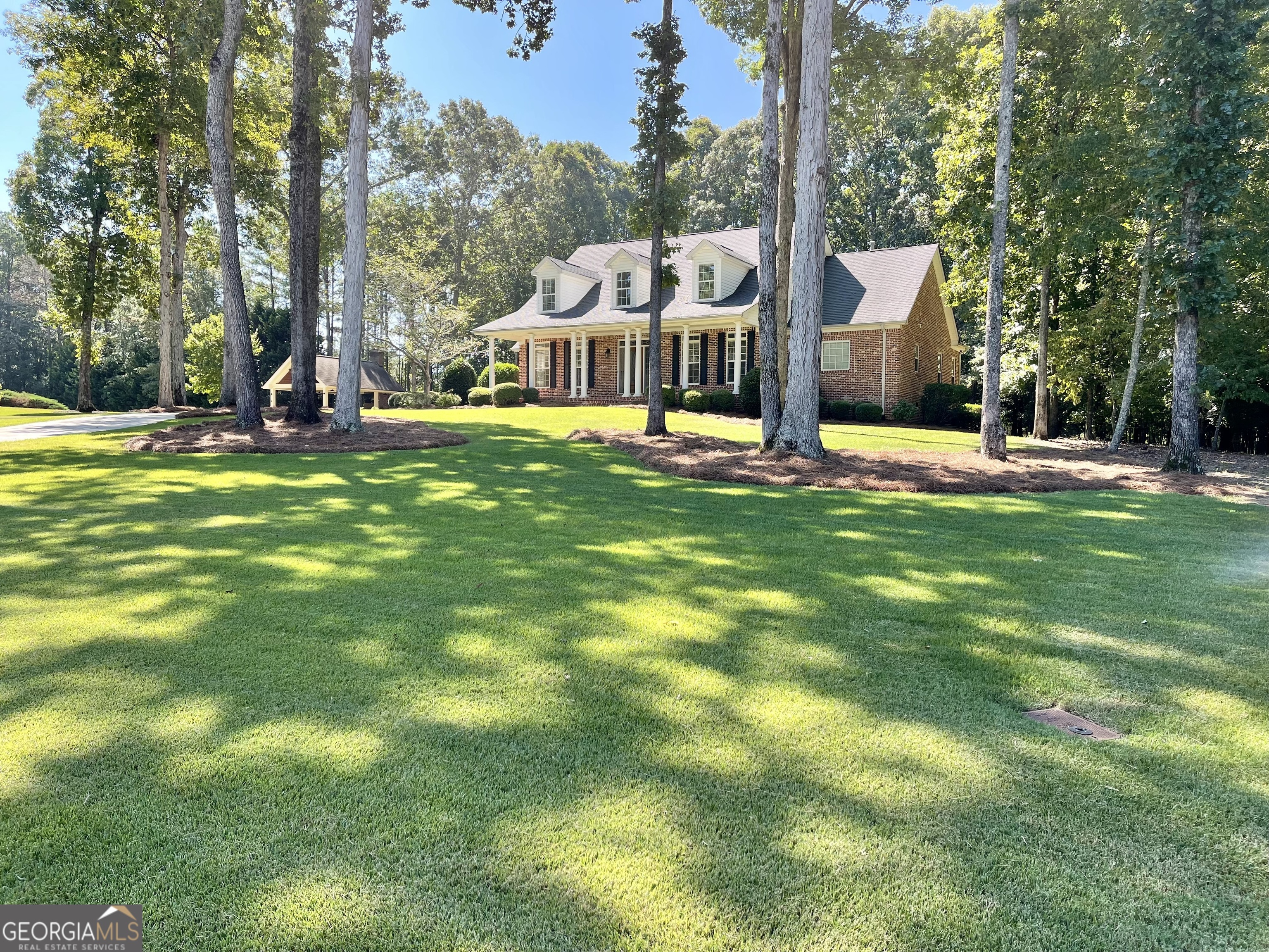 a view of a house with a big yard and large trees