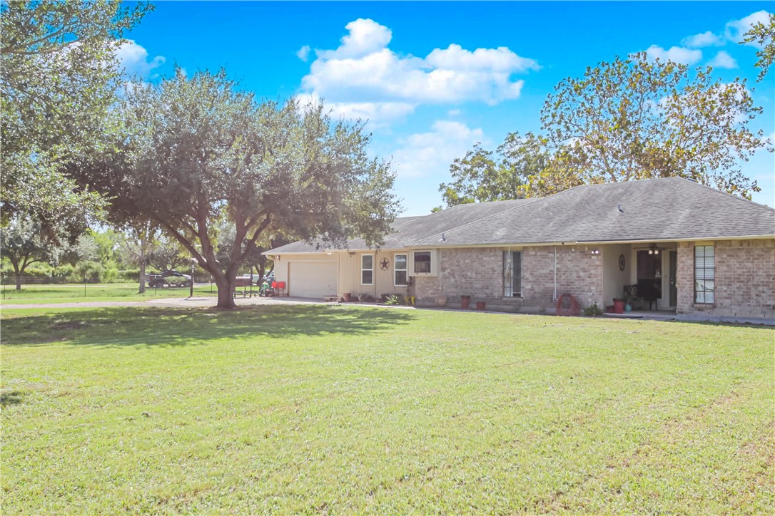 a view of a house with a yard and a large tree