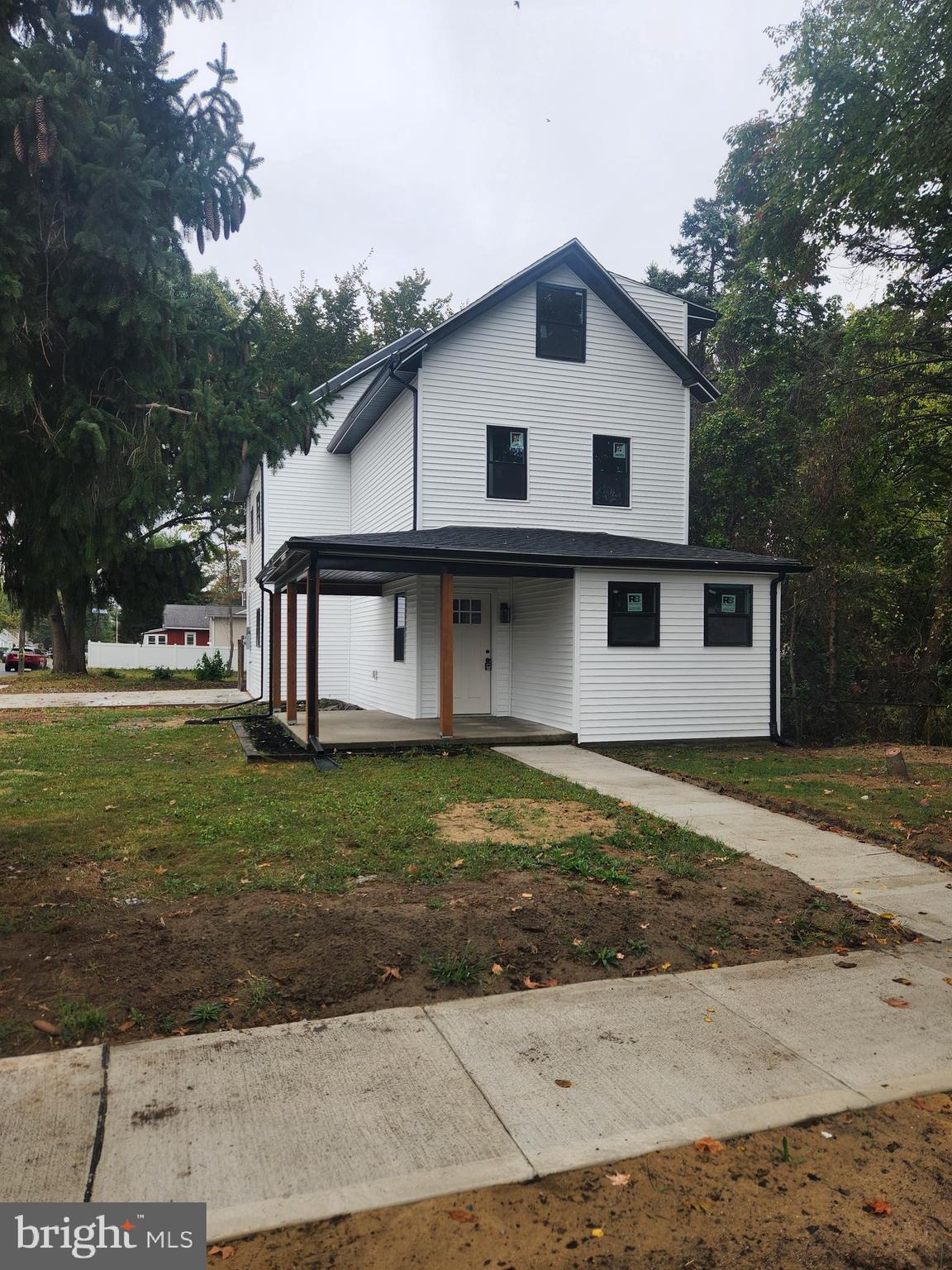 a view of a white house next to a yard with big trees