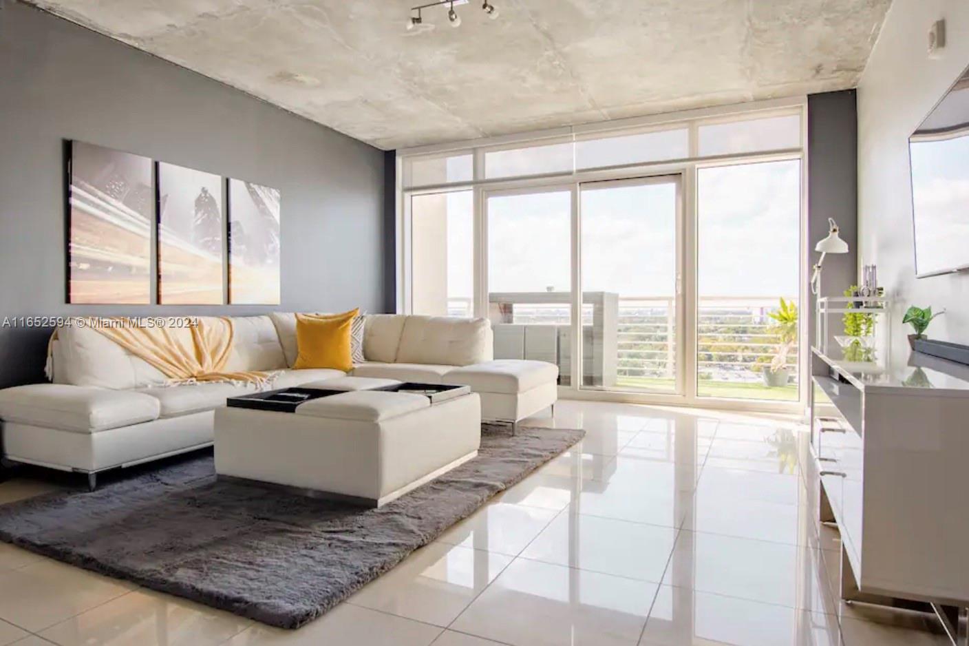 a living room with furniture large windows and wooden floor