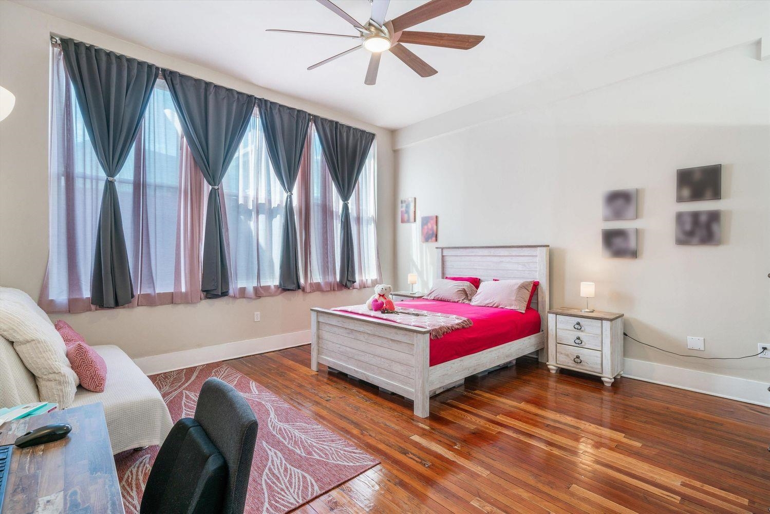 Bedroom featuring ceiling fan, dark hardwood / wood-style flooring, and multiple windows