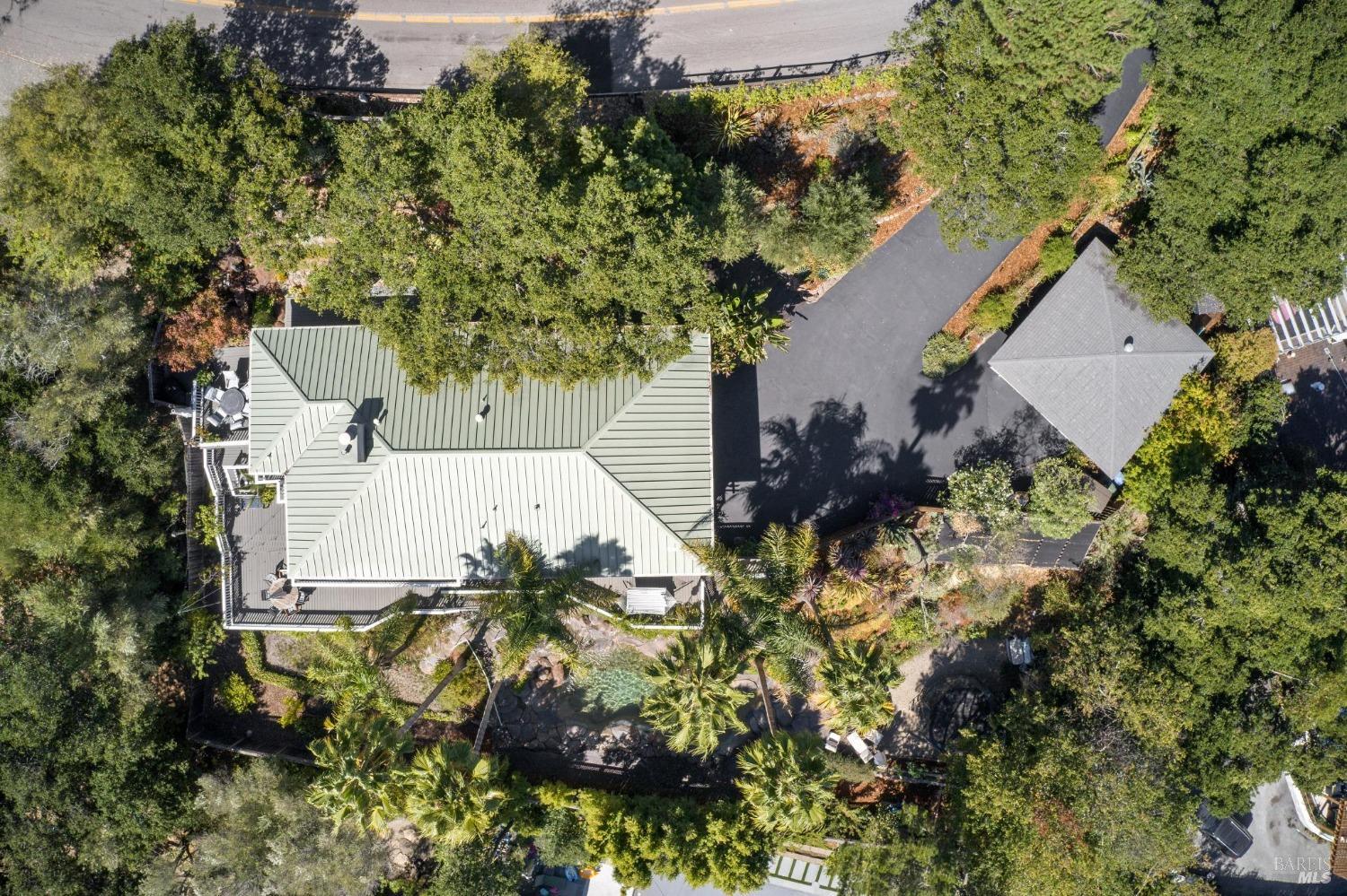 an aerial view of residential house with outdoor space and trees all around