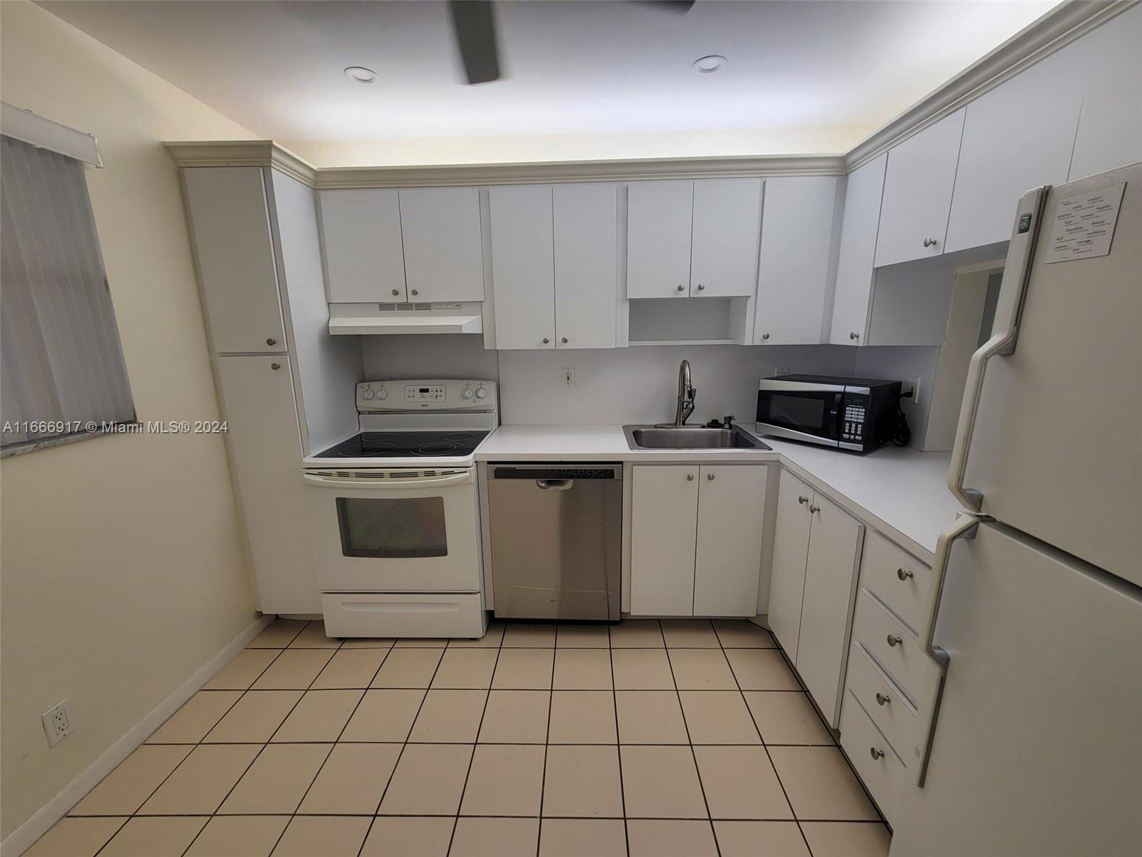 a kitchen with white cabinets a sink stove and refrigerator