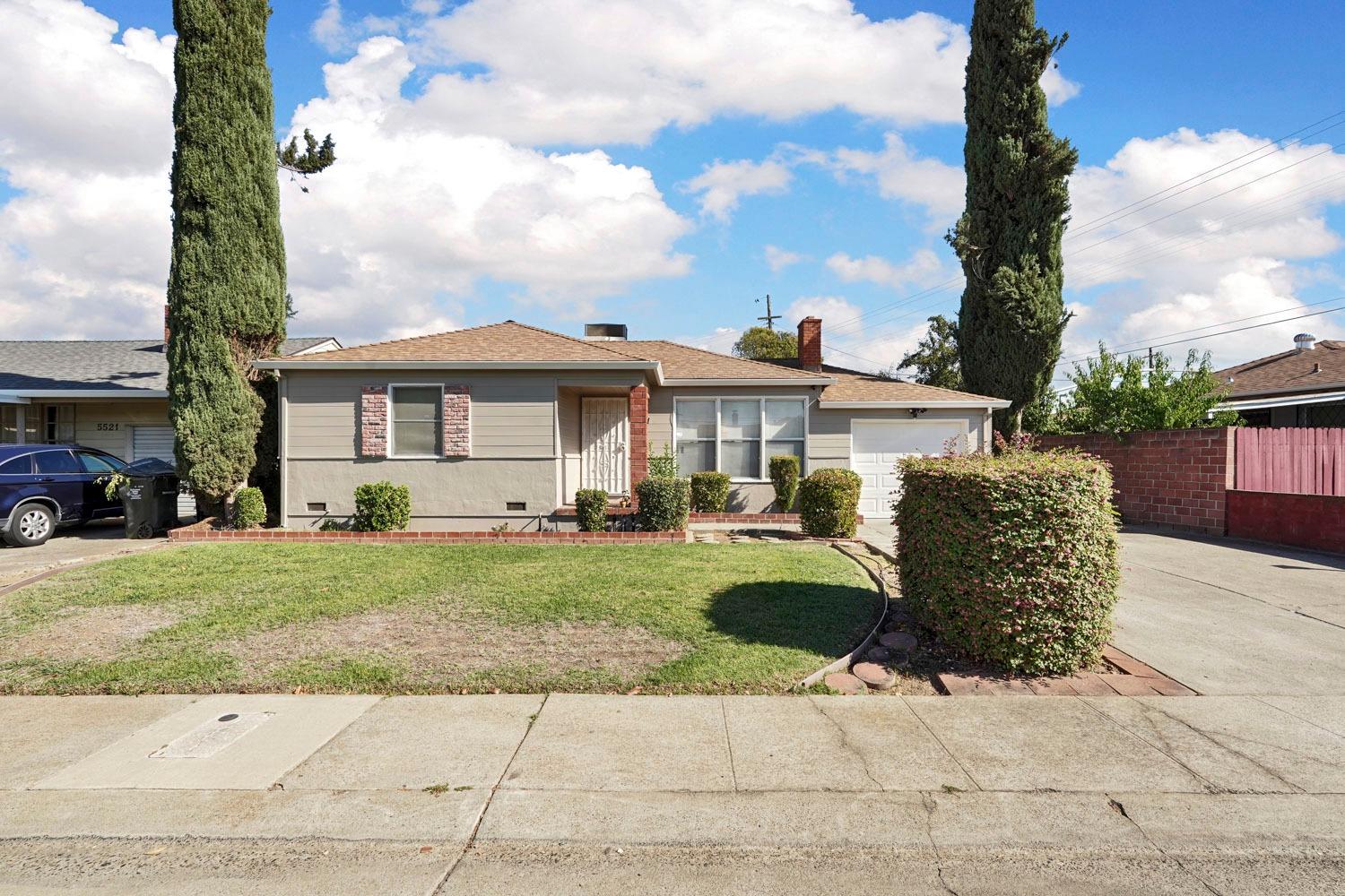 a front view of a house with a garden and trees