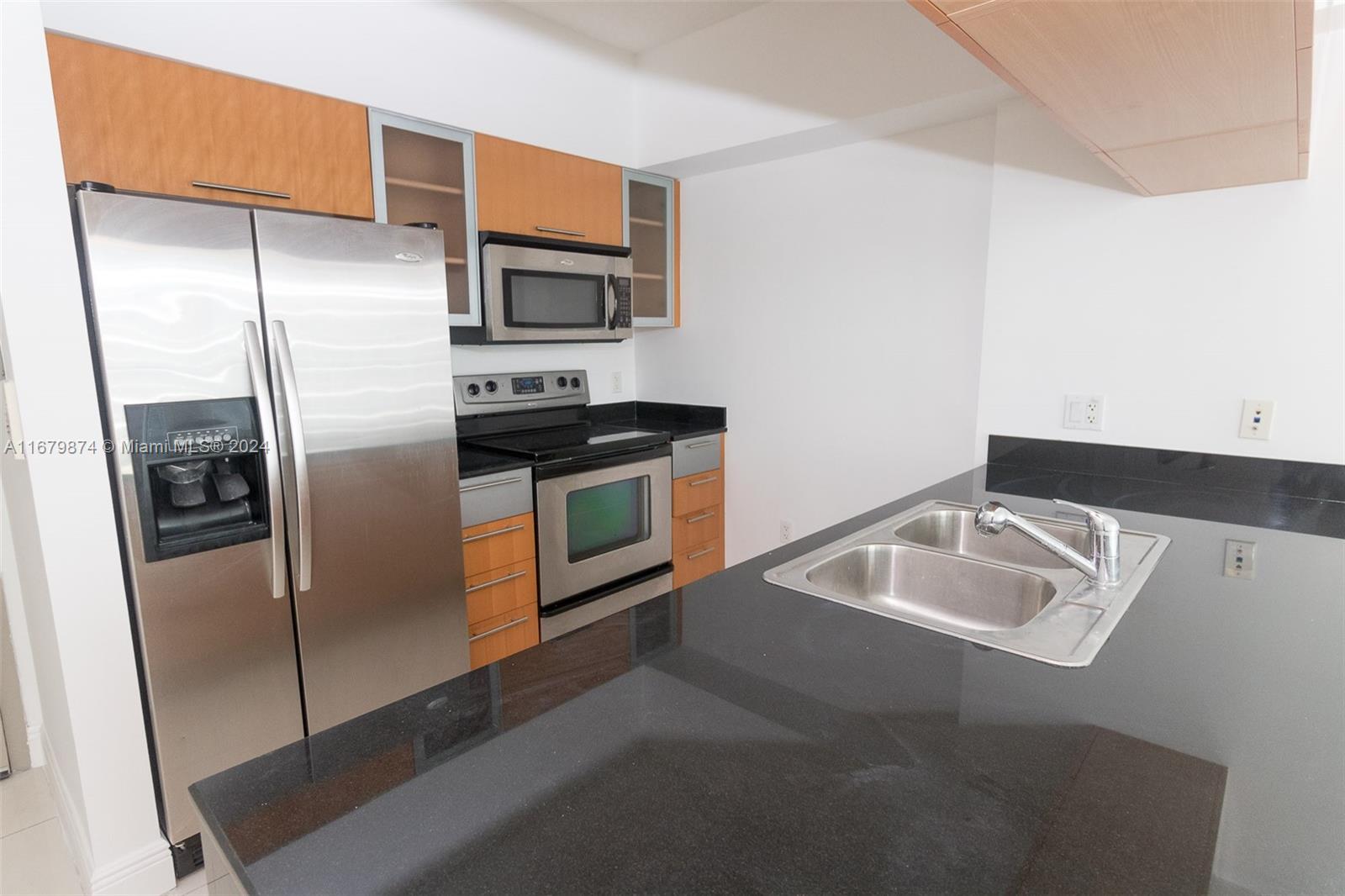 a kitchen with stainless steel appliances granite countertop a refrigerator a stove and a sink with wooden floor