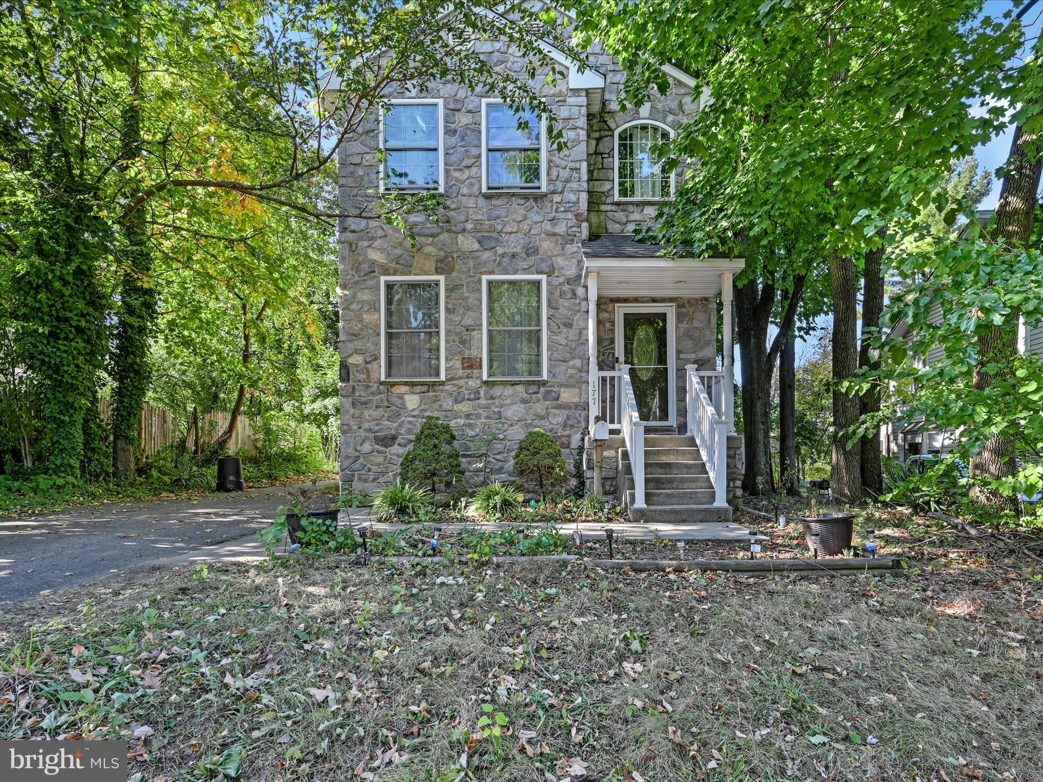 a view of a brick house with yard and large trees