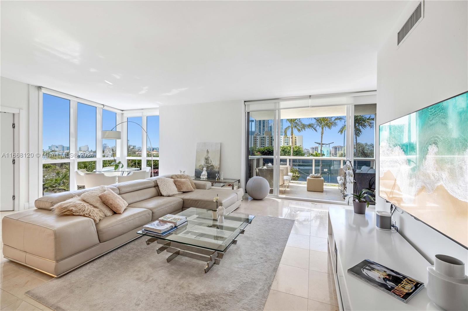 a living room with furniture large windows and wooden floor